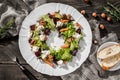 Christmas wreath salad with fresh carrots, beets, nuts, cheese, lettuce and arugula on plate on rustic wooden table.