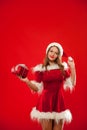 Christmas, x-mas, winter, happiness concept - smiling woman in santa helper hat with gift box, over red background Royalty Free Stock Photo