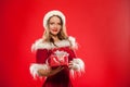 Christmas, x-mas, winter, happiness concept - smiling woman in santa helper hat with gift box, over red background Royalty Free Stock Photo