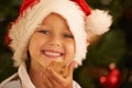 Christmas, young child with cookie and smile in portrait, holiday and celebration in family home. Happy kid, chocolate