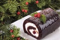 Christmas yule log cake on plate under tree Royalty Free Stock Photo