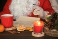 Santa Claus reading letter, drinking tea and eating tangerines. Royalty Free Stock Photo