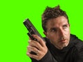 Chroma key green background action portrait of serious and attractive hitman or special agent man holding gun pointing the handgun