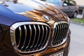 Chrome BMW logo sign close-up. Front hood and car grill of black blue BMW on an outdoor parking on a sunny day Royalty Free Stock Photo