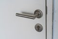 Chrome door handle and lock with key on white door