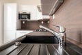 Chrome faucet in a brand new kitchen with blurred background with microwave oven and fridge in a reconstructed home