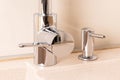 Chrome faucet and liquid soap dispenser in modern kitchen with granite sink