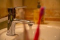 chrome faucet with open water, 2 toothbrushes and white sink Royalty Free Stock Photo