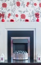 Chrome fire surround with rose flower wall paper over the top