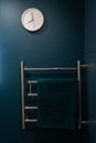 Chrome heated towel rail on dark background in blue and green bathroom Royalty Free Stock Photo