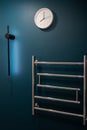 Chrome heated towel rail on dark background in blue and green bathroom Royalty Free Stock Photo
