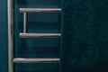 Chrome heated towel rail on dark background in blue and green bathroom Royalty Free Stock Photo