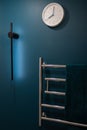 Chrome heated towel rail on dark background in blue and green bathroom Royalty Free Stock Photo