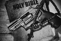 Revolver and cross on an old bible on a wooden table Royalty Free Stock Photo