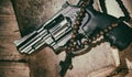 Revolver and cross on an old book on a wooden table Royalty Free Stock Photo