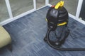 A chrome upright vacuum cleaner placed on the carpeted flooring at the corner of an office space