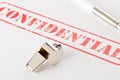 Chrome whistle on documents with confidential top secret information on wooden office desk - whistleblower concept Royalty Free Stock Photo