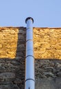 Chromed metal smokestack attached to a dry stone wall