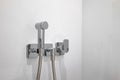 Chromium bidet shower with whitle tile in a toilet. Clean and new spray shower. Royalty Free Stock Photo