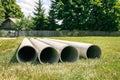 Chrysotile Cement Pipes Lie On The Green Grass Of Construction Site. Four Round Tubes. Copy Space. Building Element. Column
