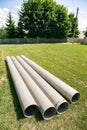 Chrysotile Cement Pipes Lie On The Green Grass Of Construction Site. Four Round Tubes. Copy Space. Building Element. Column