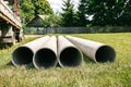 Chrysotile cement pipes lie on the green grass of construction site. Four round tubes. Copy space. Building element. Column