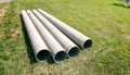 Chrysotile cement pipes lie on the green grass of construction site. Four round tubes. Copy space. Building element. Column