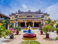 Chua Phap Bao Pagoda through a courtyard garden with flowers and bonsai trees, Hoi An, Vietnam