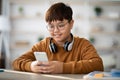 Chubby Asian Boy Enjoys Mobile Gaming at Home With Wireless Headset On Royalty Free Stock Photo