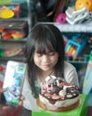 Chubby Asian little girl celebrating her birthday at home. Happy and jovial in front of the cake. Soft focus Royalty Free Stock Photo