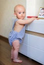 Chubby baby learning to stand up holding on to the furniture Royalty Free Stock Photo