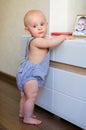 Chubby baby learning to stand up holding on to the furniture Royalty Free Stock Photo