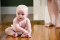 Chubby baby sitting on floor wearing diaper