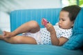 Chubby baby using a pink cell phone by herself on the sofa Royalty Free Stock Photo