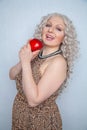 Chubby blonde girl wearing summer dress and posing with big red apple on white background alone Royalty Free Stock Photo