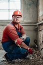 Chubby builder on a construction site working on a brick wall with a hammer Royalty Free Stock Photo