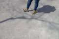 Chubby female wearing  tight blue jeans and golden white fashion sneakers waiting on a sidewalk with shadow and tree branch shadow Royalty Free Stock Photo