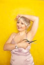 Chubby girl in dress with unshaven hairy armpits and scissors in hand on yellow background in Studio Royalty Free Stock Photo