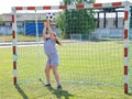 Chubby girl in sportswear stands in football gate and catches ball with her hands