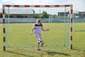 Chubby girl in sportswear stands in football gate and beats ball with his foot