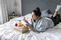 Chubby hispanic woman having breakfast in bed while using the phone in Latin America, plus size female Royalty Free Stock Photo
