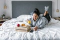 Chubby hispanic woman having breakfast in bed while using the phone in Latin America, plus size female Royalty Free Stock Photo