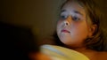 chubby little girl is playing video games by tablet in bed in night time