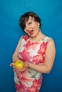 Chubby plus size woman holding green apple on blus studio solid background