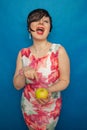 Chubby plus size woman holding green apple on blus studio solid background