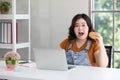 Chubby woman eating a hamburger while working from home Royalty Free Stock Photo