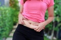 Chubby woman hand holding her own belly fat at outdoor. Royalty Free Stock Photo