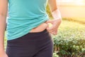 Chubby woman hand holding her own belly fat at outdoor under the Royalty Free Stock Photo