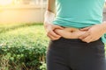 Chubby woman hand holding her own belly fat at outdoor under the Royalty Free Stock Photo