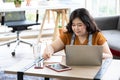 Chubby woman looking at laptop computer and writing on notebook for work or study